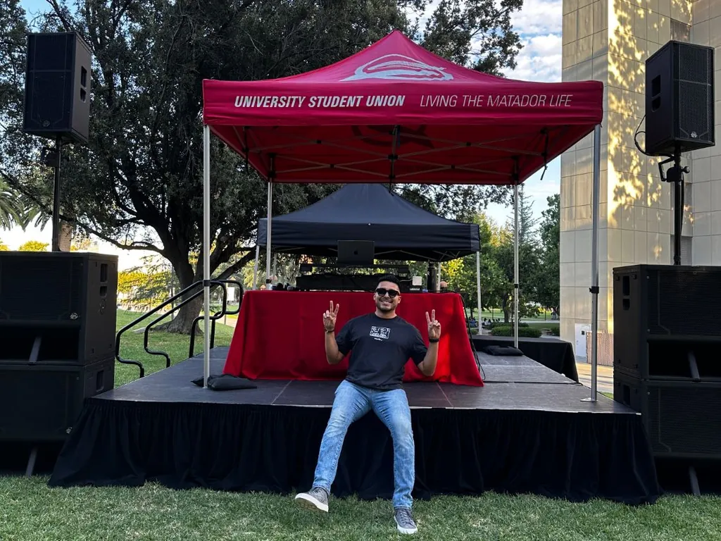 DJ Lowso on the stage at CSUN’s University Student Union, with a full sound system and the USU canopy
